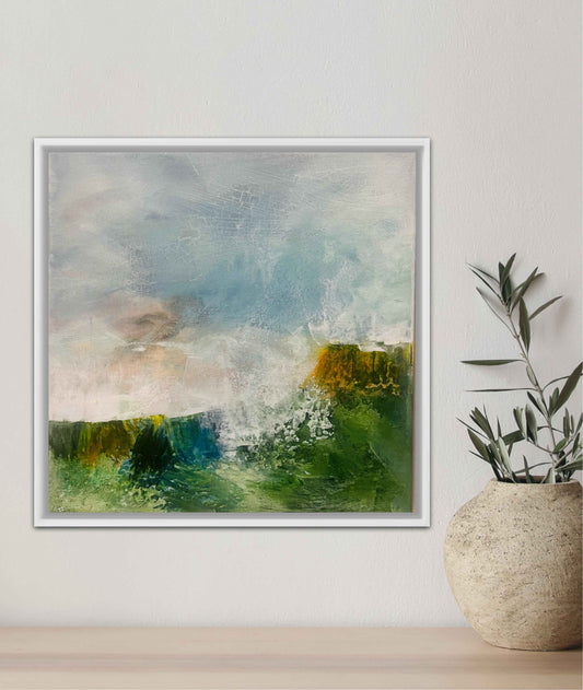 Framed small landscape painting on wall next to a vase with plants
