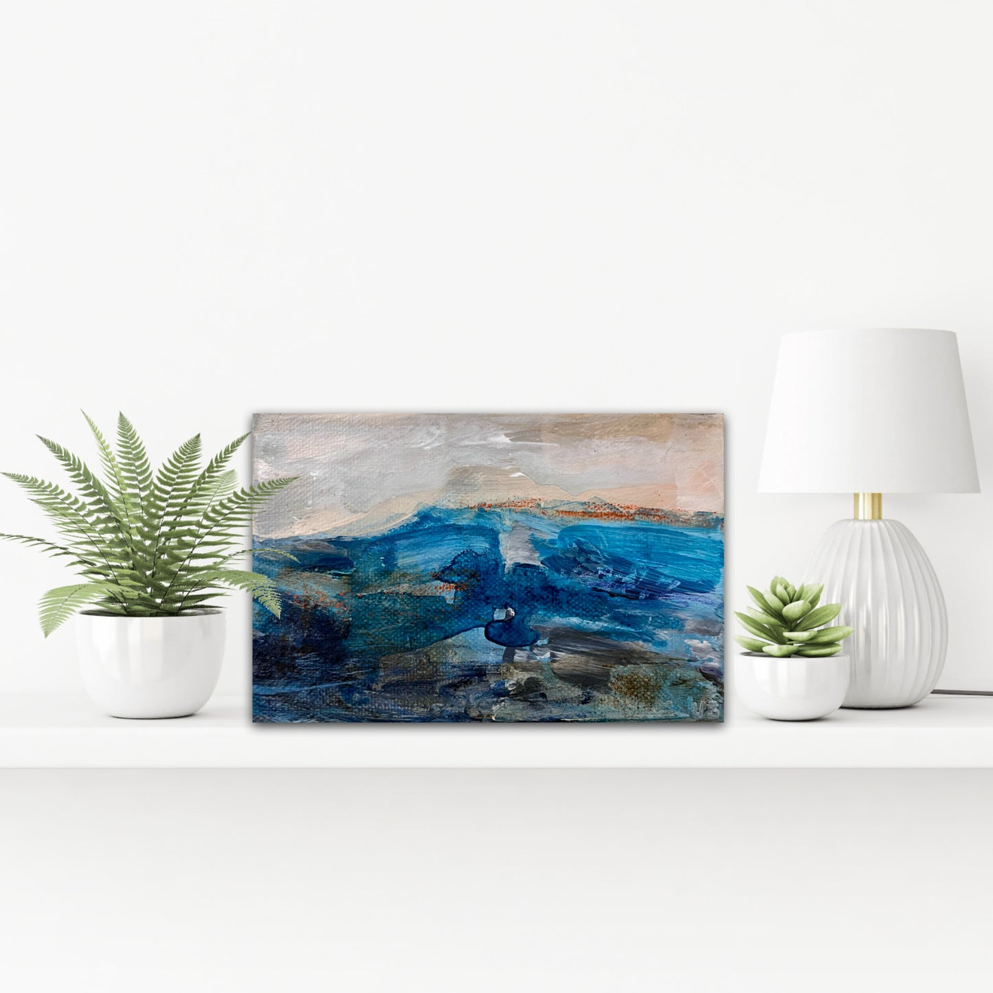 Fragments of Calm I original small contemporary landscape painting on chunky box canvas by British artist Nicola Briggs on a white shelf with plants