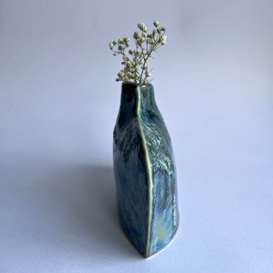textured Ceramic vase with a sflowrers inside on a light gray background