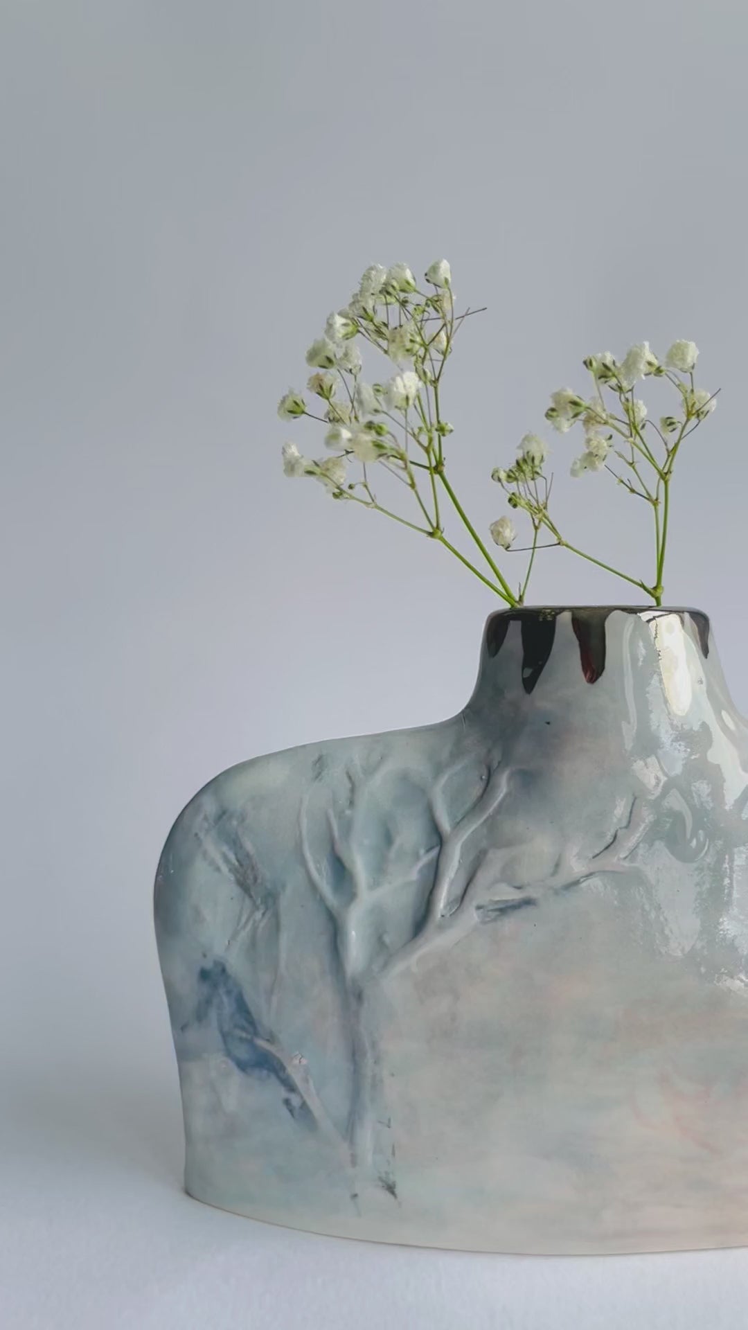 close up video of relief Winter Tree detail on hand formed Silhouette Bottle vase in grey and pale pink by ceramicist Nicola Briggs