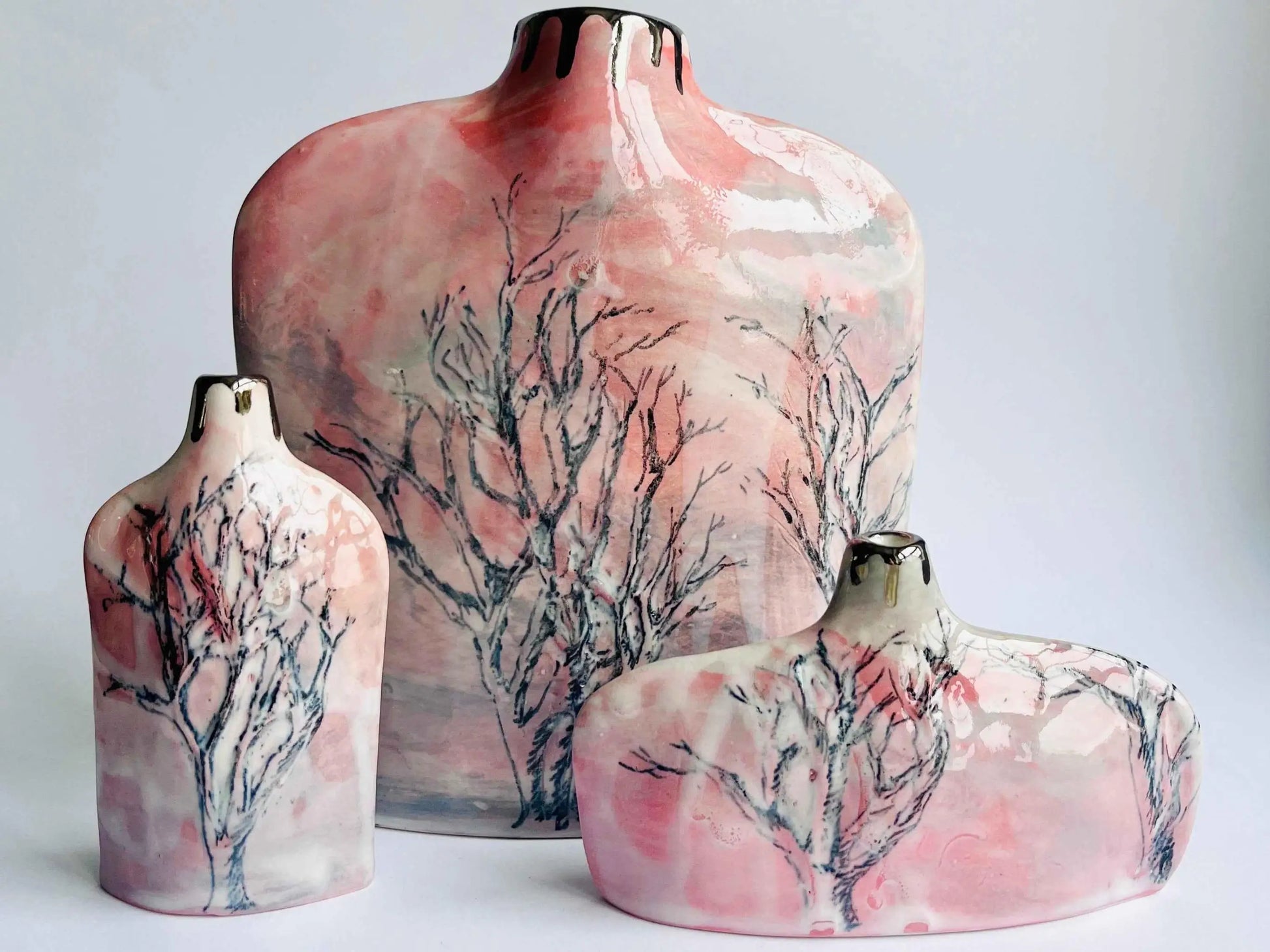 Set of three ceramic vases with tree design on a light gray background