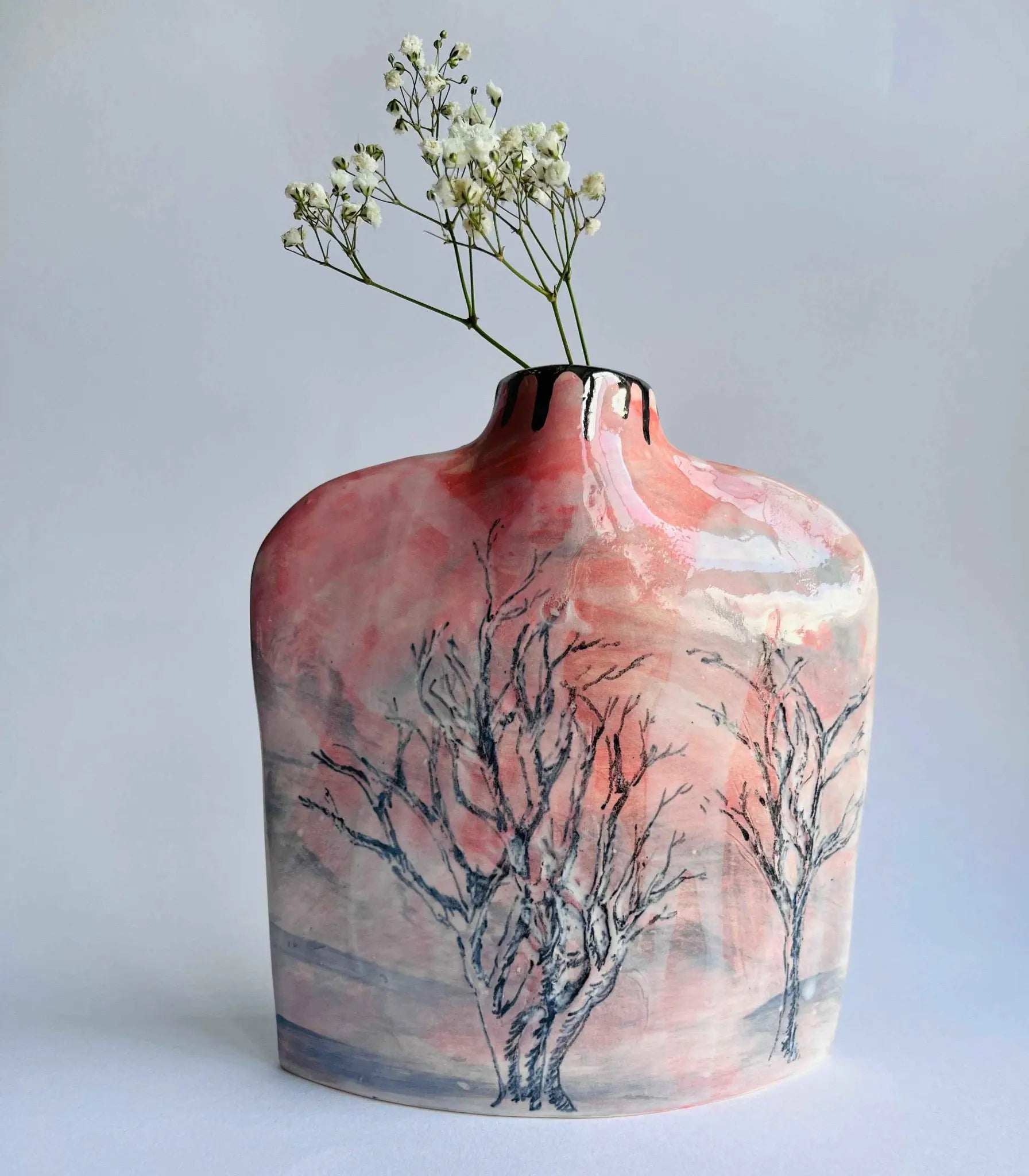 Ceramic vase with tree design and white flowers on a light gray background