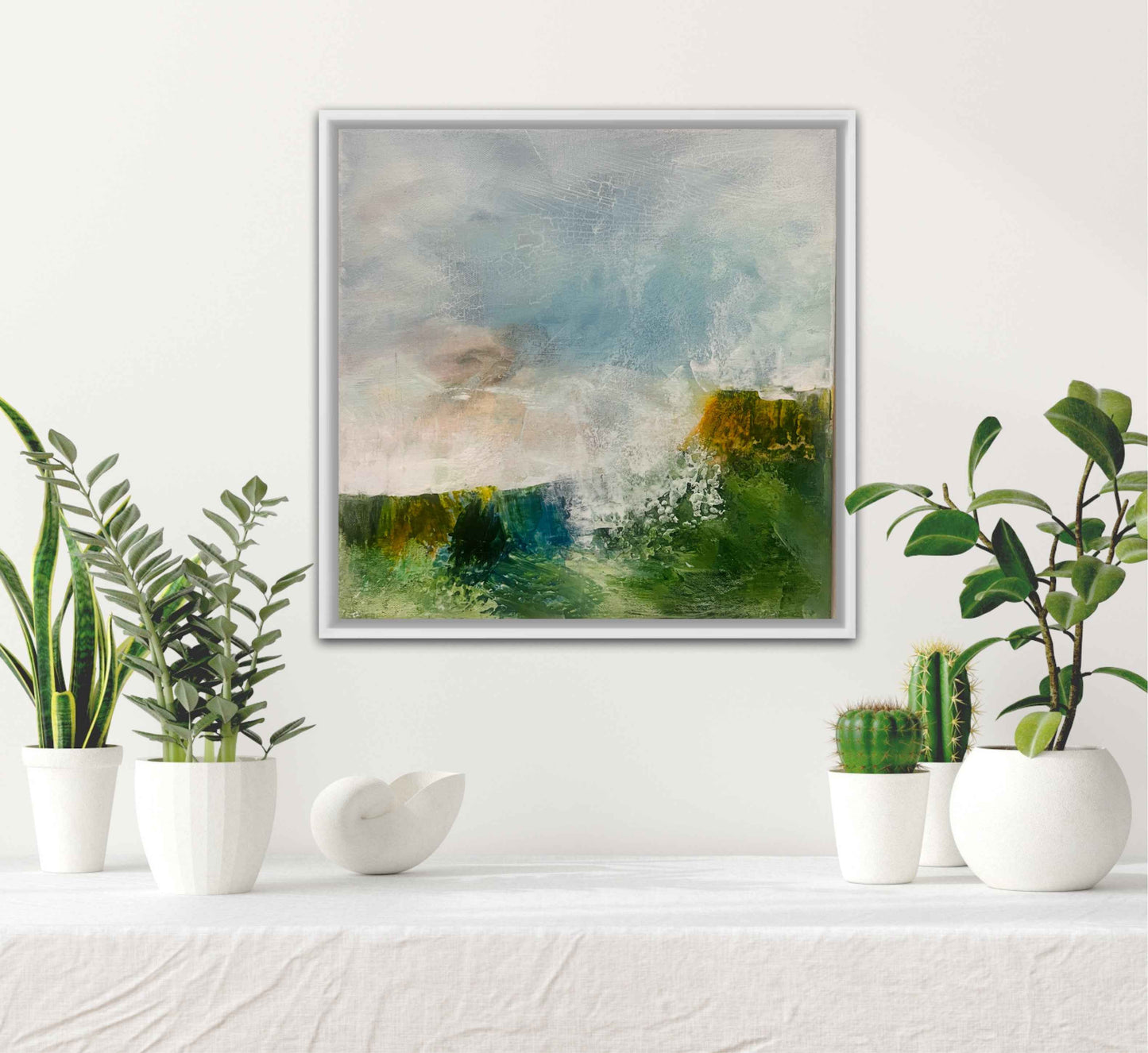 Framed abstract landscape painting on a wall with potted plants below