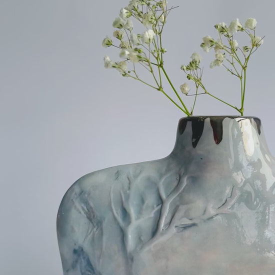 close up video of relief Winter Tree detail on hand formed Silhouette Bottle vase in grey and pale pink by ceramicist Nicola Briggs 