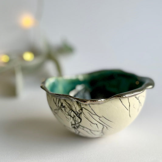 Green glazed porcelain feather bowl with unglazed exterior and platinum lustre detail on the rim, handbuilt in her garden studio by Nicola Briggs Ceramics 